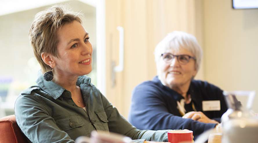 Twee vrouwen zitten aan tafel in een gesprek